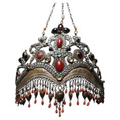 Uzbekistan, Tajikistan: a rare, old ‘bridal crown’ made of silver, gilded in parts, with turquoise coloured ornamental stones, glass, coral, and many pendants. Uzbek and Tajik women wore these ‘bridal crowns’ for the first time at their weddings and then later at important family celebrations. This luxurious jewellery was produced by Tajik craftsmen in Samarkand and Bukhara and passed on from generation to generation. The present ‘bridal crown’ consists of a sheet silver that has been cut and pu Glass Coral, Crown Hat, Ancient Jewelry, Bridal Crown, Colored Gems, Family Celebrations, Silver Pendants, Turquoise Color, Headdress