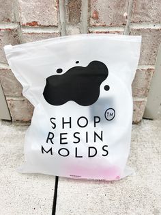 a bag that is sitting on the ground next to a brick wall with a sign reading shop resinin molds