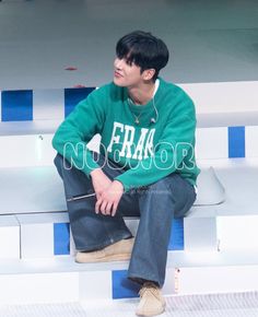 a young man sitting on top of some white and blue steps with headphones in his ears