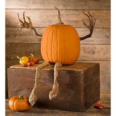 an orange pumpkin sitting on top of a wooden box with antlers and other decorations around it