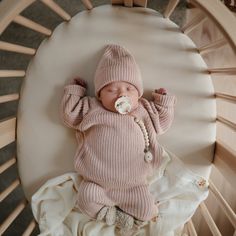 a baby in a pink sweater and hat is sleeping