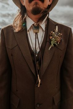 a man with long hair wearing a brown suit and hat