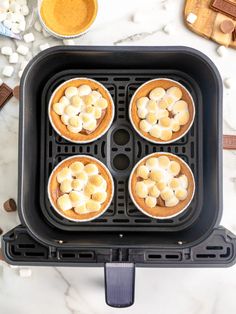 four mini pies in a black pan with marshmallow toppings on top