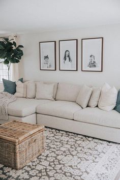 a living room with white couches and pictures on the wall above it's coffee table