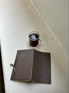 an open book with a cup of coffee next to it on a white table top