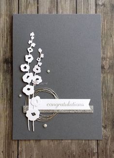 a card with some flowers on it and the words congratulations written in silver foil,