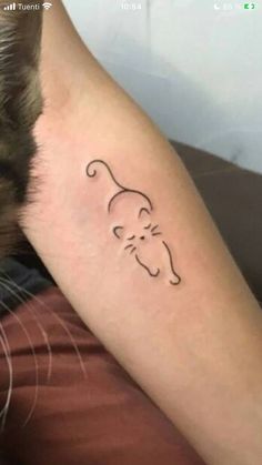 a small cat tattoo on the arm of a person's left arm, which has an outline of a cat