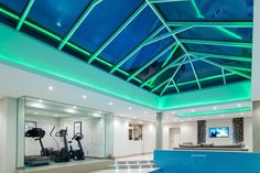 an indoor gym with treadmills, exercise equipment and blue skylight ceilinging