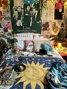 a bed covered in lots of pillows and blankets next to a wall with posters on it