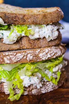 there is a sandwich with lettuce and cheese on the side, sitting on a cutting board