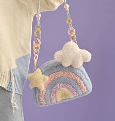 a woman is holding a crocheted purse with a rainbow and star hanging from it