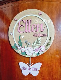 a wooden sign that says ellen and has flowers on the front with butterflies around it