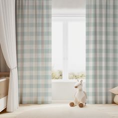 a stuffed animal sitting in front of a window with blue and white checkered curtains