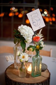 there are flowers in vases on the table with candles and a sign that says 5