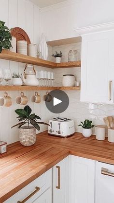 a kitchen with white cabinets and wooden counter tops, filled with pots and pans