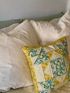 a white bed topped with pillows and a green pillow on top of it's headboard