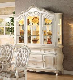 a white china cabinet with glass doors and chairs