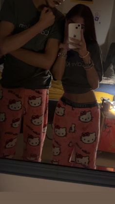 a man and woman taking a selfie in the mirror with hello kitty pajama pants