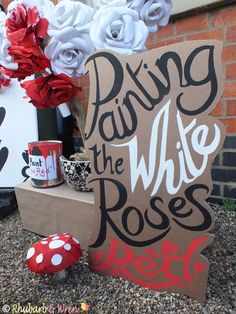 a sign that says dying the white roses next to some red and white paper flowers