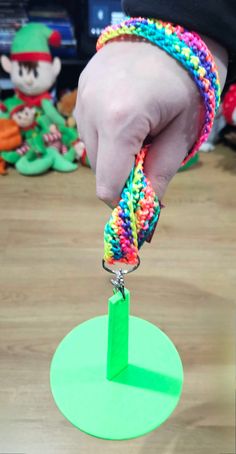 a person is holding onto a bracelet with a green circle on the floor next to other toys