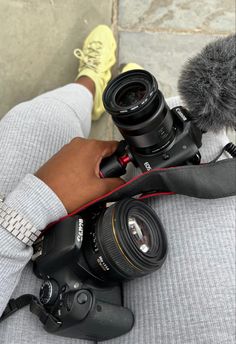 a person holding a camera with a microphone in front of them and the photographer's feet