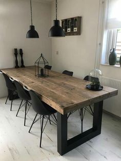 a dining room table with black chairs and hanging lights