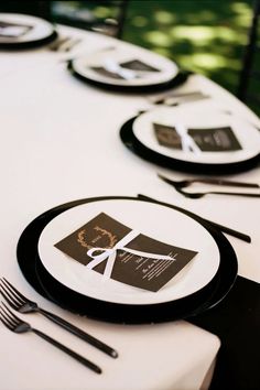 the table is set with black and white plates, silverware, and napkins