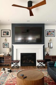 a living room with a large flat screen tv mounted above the fireplace and two couches