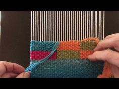 two hands are working on a weaving project