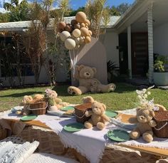 some teddy bears are sitting at a picnic table with food and balloons in the air