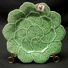 a green and white plate with gold handles on a black tableclothed background is shown