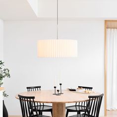 a dining table with four chairs and a white light hanging from the ceiling over it