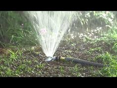 a sprinkler is spraying water on the ground in front of some grass