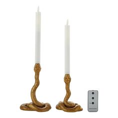 two candles are sitting next to each other with a remote control in front of them