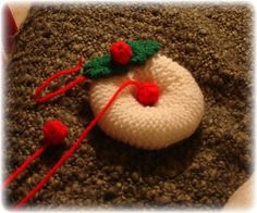 a crocheted snowman ornament is laying on the ground next to two red pins