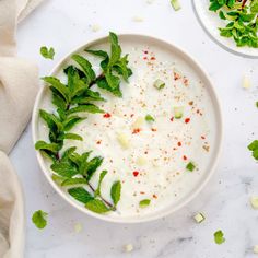 a white bowl filled with yogurt and garnished with green leaves