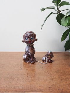 a brown dog figurine sitting on top of a wooden table next to a potted plant