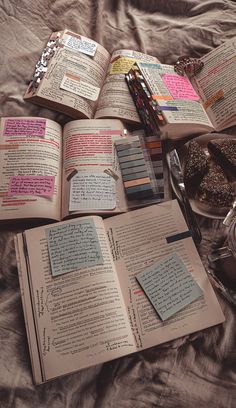 an open book sitting on top of a bed next to some writing utensils