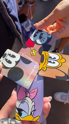 two people holding up some cartoon themed business cards in their hands with other people around them