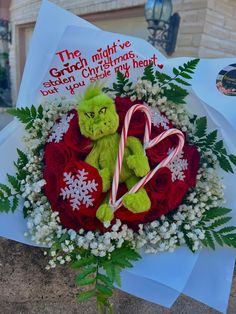 a green teddy bear sitting in a wreath with flowers and candy canes on it