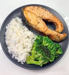 a plate with rice, broccoli and fish on it next to a baked potato