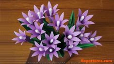 purple flowers with white tips are in a vase on a wooden table, ready to be used as a centerpiece