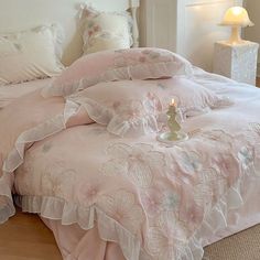 a bed with pink comforter and pillows on it in a room next to a lamp