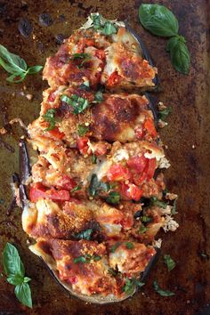 an overhead view of some food on a tray with basil leaves and sauce in it