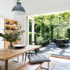 a dining room table with chairs and a bench in front of an open glass door