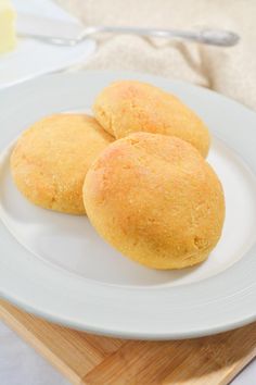 two biscuits are on a white plate next to butter