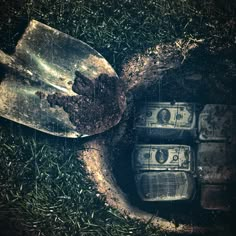 an old broken glass bottle with money in it laying on the ground next to some grass