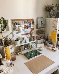 a white desk topped with lots of clutter and pictures on it's walls