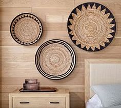 three woven baskets hanging on the wall above a bed in a room with wood paneling