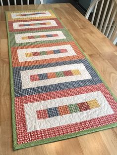 a table runner made from strips of fabric on top of a wooden dining room table